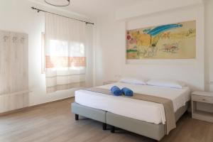 a white bedroom with a bed with blue shoes on it at Hotel Villa Cedrino in Dorgali