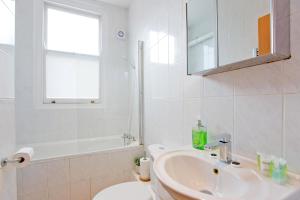 a white bathroom with a sink and a mirror at Calabria 4 Comfortable apartment in London