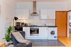 una cucina con armadi bianchi e una lavatrice/asciugatrice di Calabria 4 Comfortable apartment a Londra