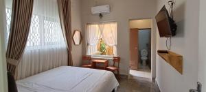 ein Schlafzimmer mit einem Bett und einem TV sowie ein Badezimmer in der Unterkunft The Bloomy House in Yogyakarta