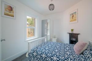 a bedroom with a blue and white bed and two windows at 3 Anzac Cottage in Cowes