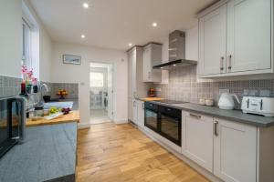 cocina con armarios blancos y suelo de madera en 3 Anzac Cottage, en Cowes