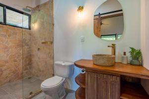 bagno con servizi igienici, lavandino e specchio di The Surf Journey Casita a Uvita