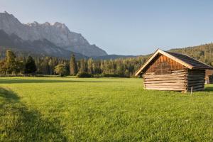 eine Holzhütte auf einem Feld mit Bergen im Hintergrund in der Unterkunft Huber Living Deluxe 108 in Germering