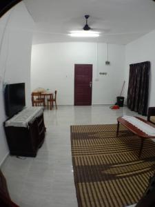 ein Wohnzimmer mit einem TV, einem Sofa und einem Tisch in der Unterkunft Sobey Laris Homestay UMK in Bachok