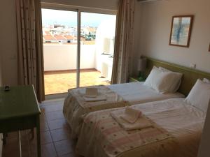 1 Schlafzimmer mit 2 Betten und einem großen Fenster in der Unterkunft Prestige for Home - Apt Alagoa Praia Altura in Altura