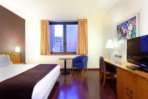 una camera d'albergo con letto, scrivania e TV di Hotel Viladomat by Silken a Barcellona
