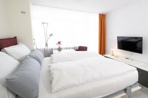 a white bedroom with a couch and a tv at Huber Living Basic 102 in Germering