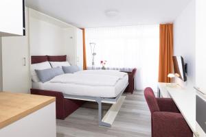 a bedroom with a white bed and a couch at Huber Living Basic 102 in Germering