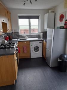 a kitchen with a refrigerator and a washing machine at Comfort, peace and quiet guaranteed in this 3 bed in West Auckland