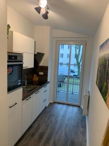 uma cozinha com armários brancos e uma porta de vidro deslizante em 40 qm Appartment Parkplatz, Balkon,Netflix, Prime em Chemnitz