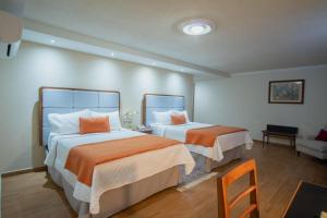 sypialnia z 2 łóżkami z pomarańczową i białą pościelą w obiekcie Hotel del Parque w mieście Matehuala