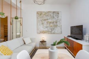 a living room with a white couch and a tv at Setúbal Downtown Apartments in Setúbal