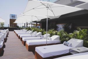 a row of white beds on a deck with umbrellas at Hotel Faro, a Lopesan Collection Hotel - Adults Only in Maspalomas