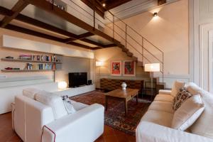 un soggiorno con 2 divani bianchi e una TV di Palazzo Orsucci Apartment a Lucca