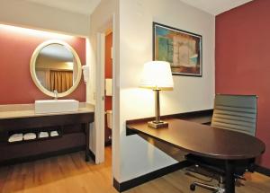 Una habitación de hotel con un escritorio y un espejo. en Red Roof PLUS Chicago - Hoffman Estates, en Hoffman Estates