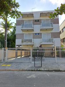 un bâtiment avec une clôture et un banc devant lui dans l'établissement Apto Enseada, 2 quadras da praia - 2 quartos com ar condicionado - 6 hospedes, à Guarujá