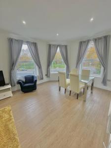 een woonkamer met een tafel, stoelen en ramen bij La Fontaine Court Apartments - Aldershot in Aldershot