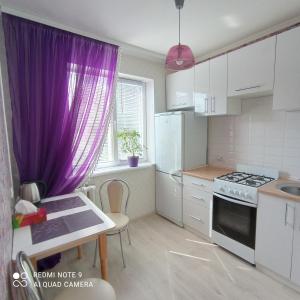 eine Küche mit lila Vorhängen und eine Küche mit Spüle in der Unterkunft Park Apartment's Світло є завжди in Dnipro