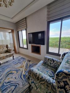 een woonkamer met een bank en een flatscreen-tv bij Villa Euphoria in Sidi Rahal