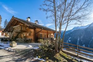 a log cabin in the mountains with a tree at Kalchgruberhof Wohnung Alpenrose in Ultimo