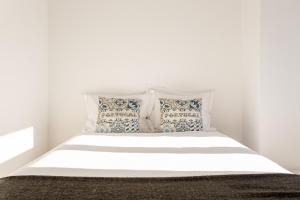 a bed with white sheets and pillows in a bedroom at ALTIDO Chic 2BR Apt in Bairro Alto, 2mins to São Pedro de Alcântara viewpoint in Lisbon