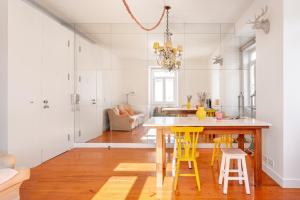 a kitchen with a wooden table and yellow stools at JOIVY Chic 2BR Apt in Bairro Alto, 2mins to São Pedro de Alcântara viewpoint in Lisbon