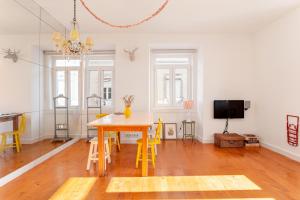 a living room with a table and yellow chairs at JOIVY Chic 2BR Apt in Bairro Alto, 2mins to São Pedro de Alcântara viewpoint in Lisbon