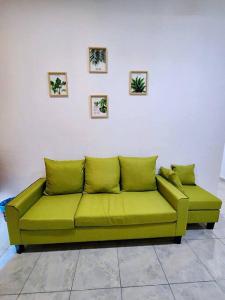 um sofá verde contra uma parede branca com imagens em Lovely & Cozy Apt In Nature City em Sandakan