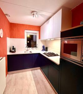 a kitchen with blue cabinets and a microwave at Villa Sudersee in Workum