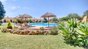 a swimming pool with two umbrellas and a yard at Arrancada 14 in Pêra