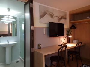 ein Badezimmer mit einem Schreibtisch mit einem Waschbecken und einem TV in der Unterkunft Somewhere to Escape - Hometel in Bangkok