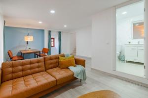 ein Wohnzimmer mit einem braunen Sofa und einem Tisch in der Unterkunft Good Vibes Apartment in Setúbal