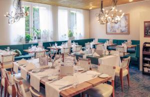 a dining room with tables and chairs and a chandelier at PLAZA INN Regensburg in Regensburg