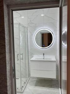 Un baño blanco con lavabo y espejo. en TbilApartments, en Tiflis