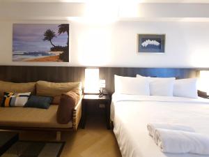 a hotel room with two beds and a couch at Somewhere to Escape - Hometel in Bangkok