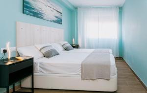 a blue bedroom with a white bed and a desk at A Casa Martinez Playa Sin Ascensor in Mareny Barraquetas