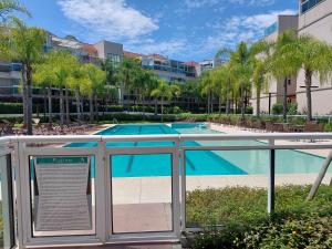 una piscina con palmeras y un edificio en Barra Garden Happy - Condomínio Barra Village Lakes tipo Resort - Recreio dos Bandeirantes, en Río de Janeiro