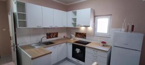 a kitchen with white cabinets and a sink and a refrigerator at Smokva in Zadar +13 photos