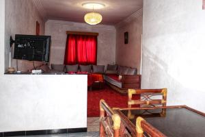 - un salon avec un canapé et un rideau rouge dans l'établissement Appartement Afgo Ouarzazate, à Ouarzazate