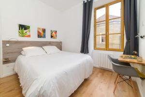 a bedroom with a white bed and a desk and a window at Le Chardonnay - Locationtournus in Tournus