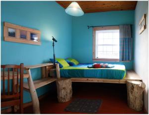 a bed in a room with a blue wall at A Barraka: rent your room in Flores! in Lajes das Flores