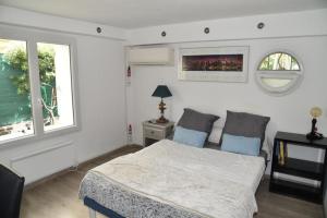 a white bedroom with a bed and two windows at Rez de chaussée de Villa Marseille 9ème in Marseille