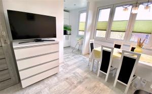 a kitchen and dining room with a flat screen tv at Apartament Słoneczny Ustka in Ustka