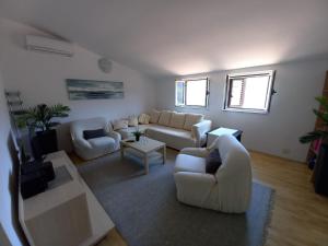 a living room with white couches and a tv at Apartman Marina sa parkingom in Jelsa