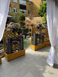 a garden with flowers in black baskets and a fence at Apartment Luxe FREE WIFI, FREE PARKING, FREE NETFLIX in Friern Barnet