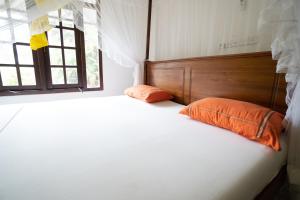 - une chambre avec un grand lit blanc et des oreillers orange dans l'établissement Happy Rest By Chill House, à Unawatuna