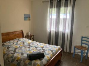 a bedroom with a bed and a chair and a window at Au coeur de la Cascade Biberon in La Plaine des Palmistes