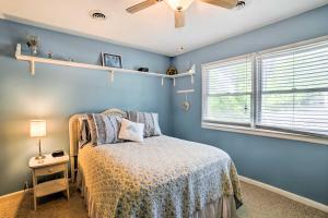 a blue bedroom with a bed and a window at Oak Island Home with Fenced Yard, Walk to Long Beach in Oak Island
