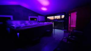 um quarto escuro com uma banheira com luzes roxas em Gites de La Croisée des Chemins - Piscine Chauffée - Spa, Hammam et Sauna em Izeaux